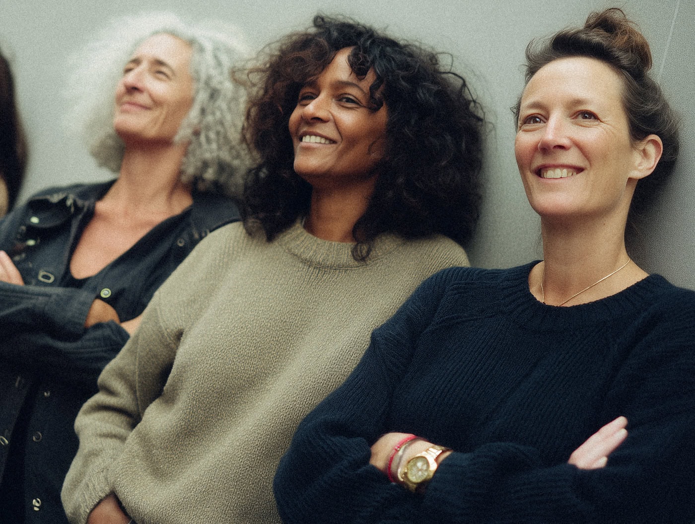 Mehrere Frauen stehen nebeneinander vor einer Wand. Sie lachen oder schauen gelassen.