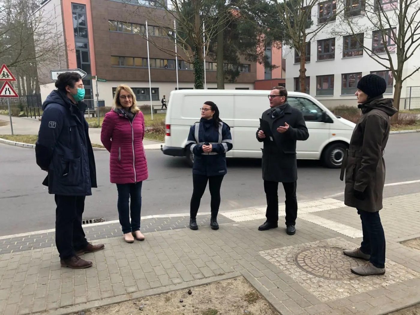 Mehrere BVV-Mitglieder stehen an einer Straße, um sich für eine Entscheidung im Verkehrsausschuss zu informieren.